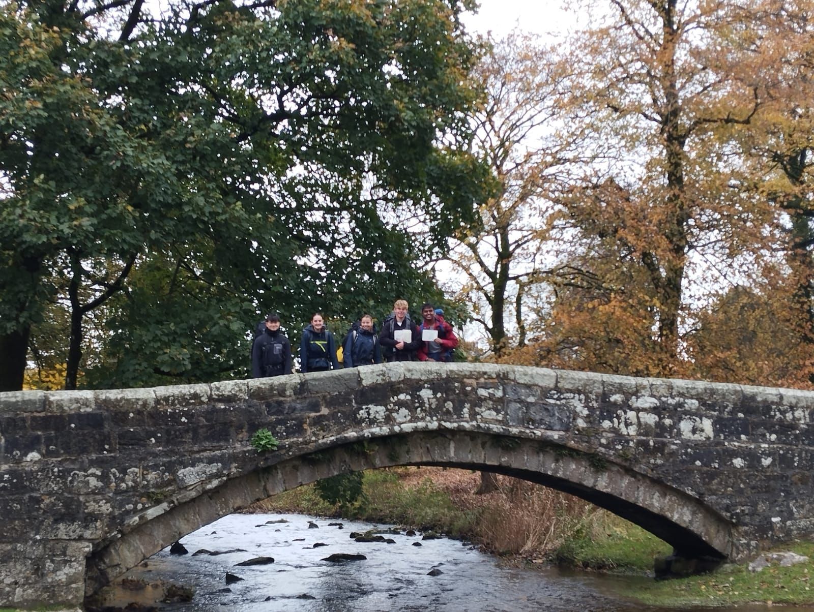 A group of people are standing in front of a stone building.