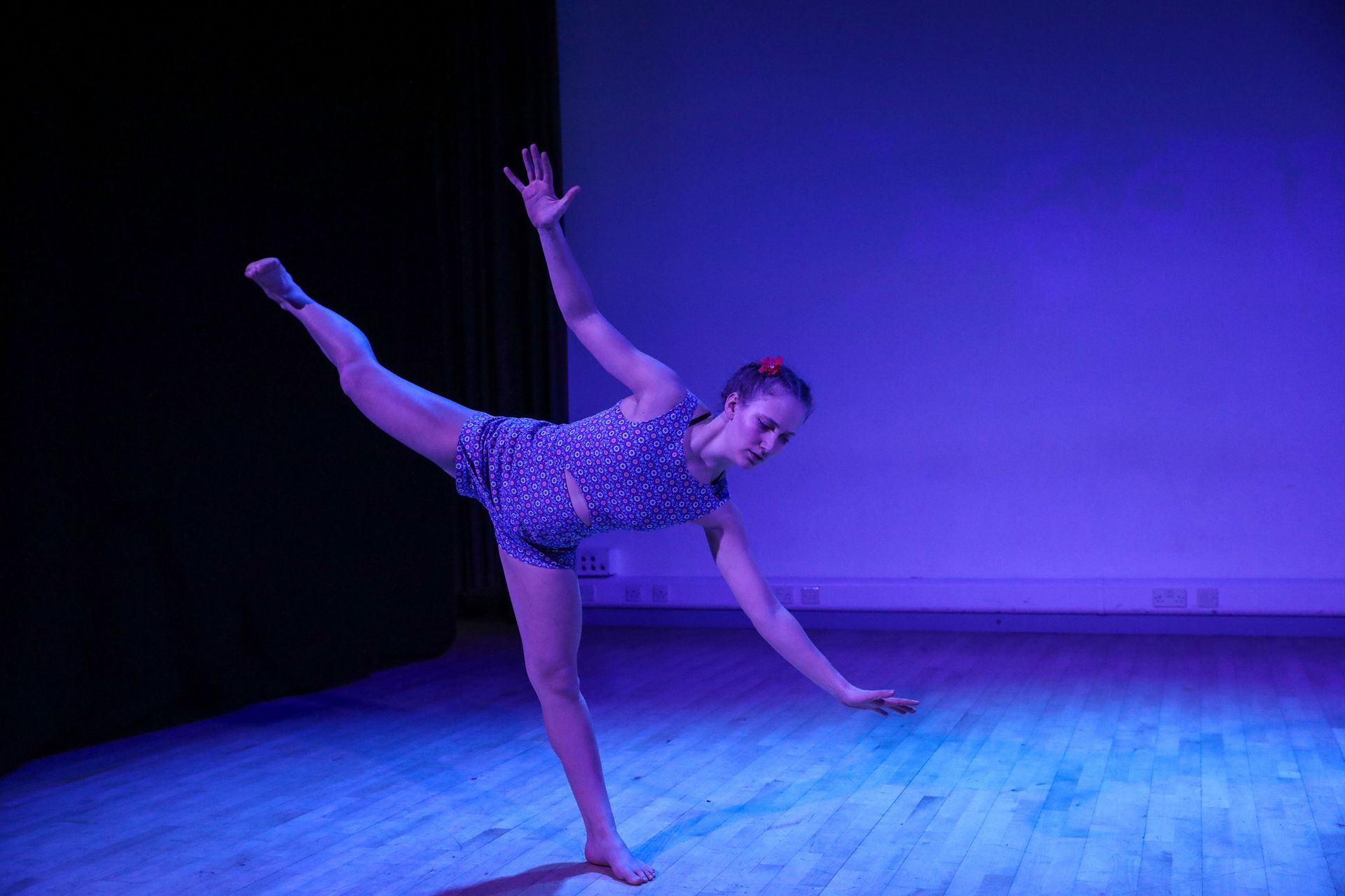A woman is dancing on a stage with purple lights.