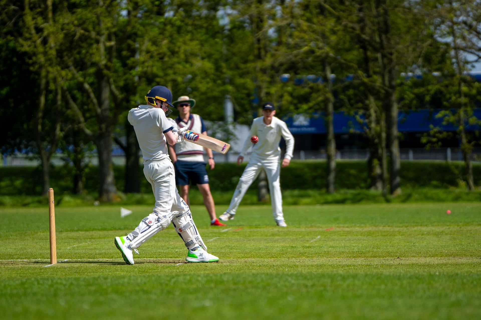 A young boy is playing a game of cricket on a field.