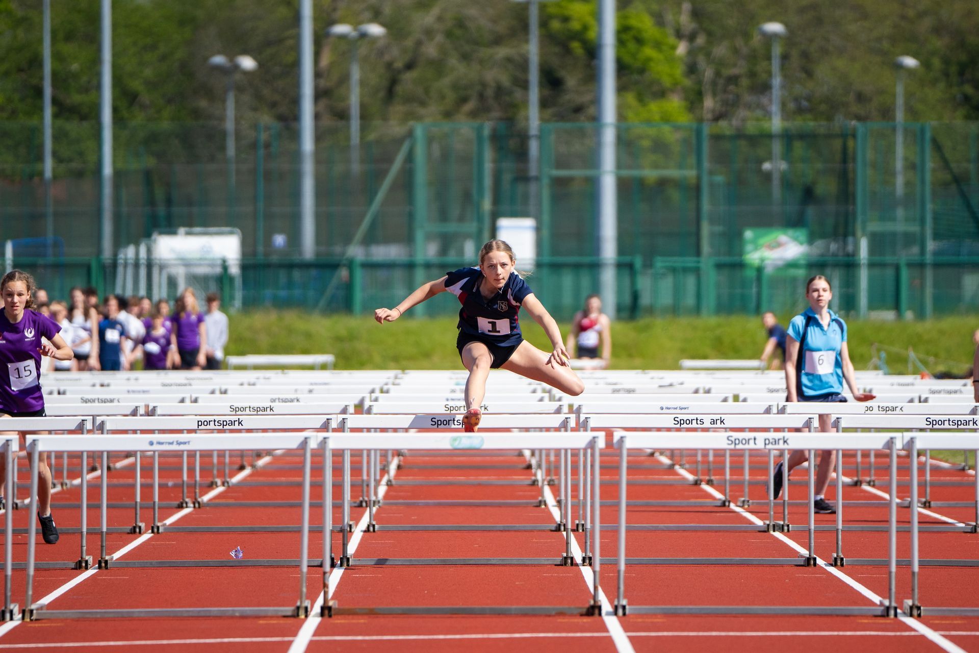 A woman is jumping over hurdles on a track.