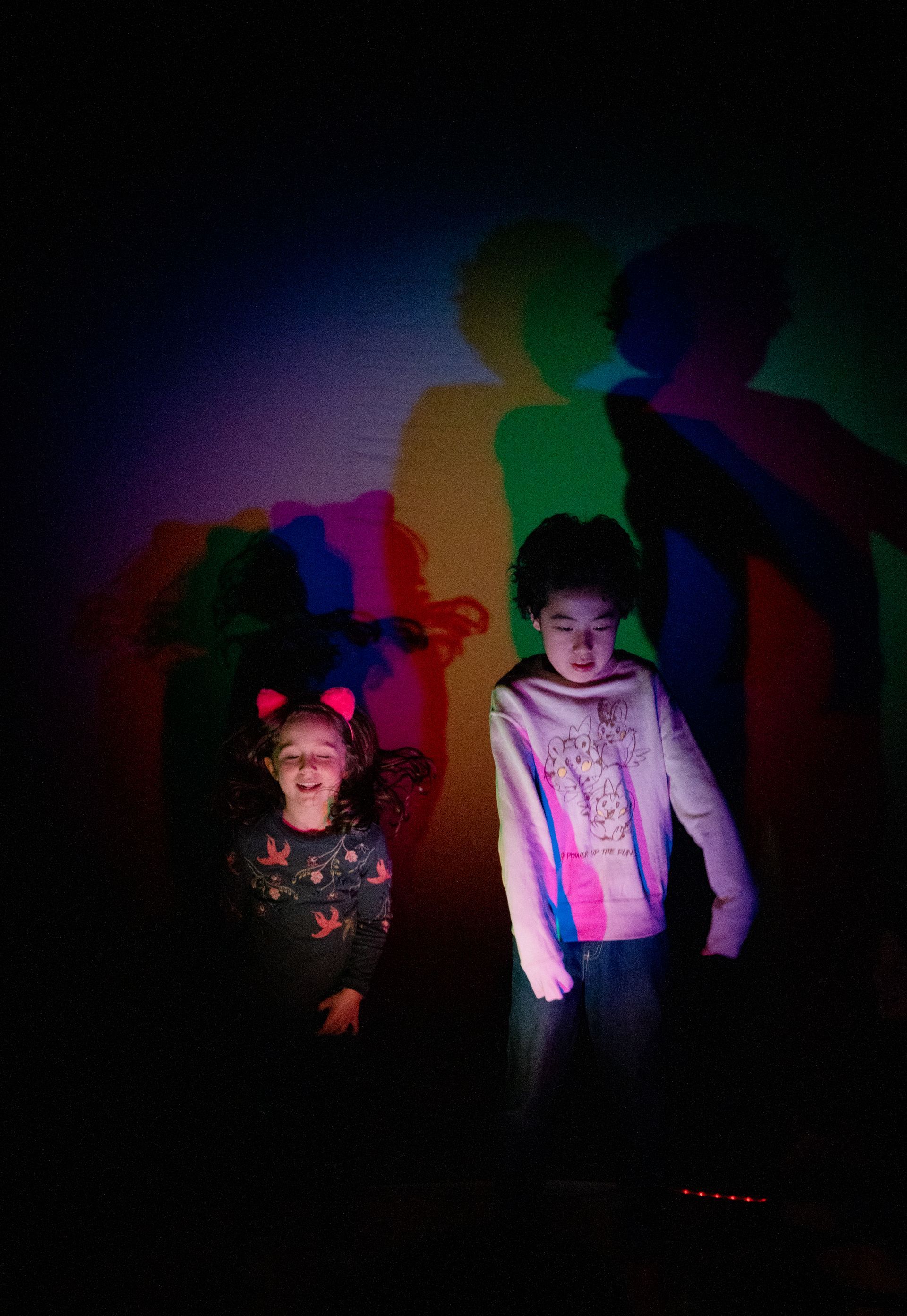 Two young girls are standing next to each other in a dark room.
