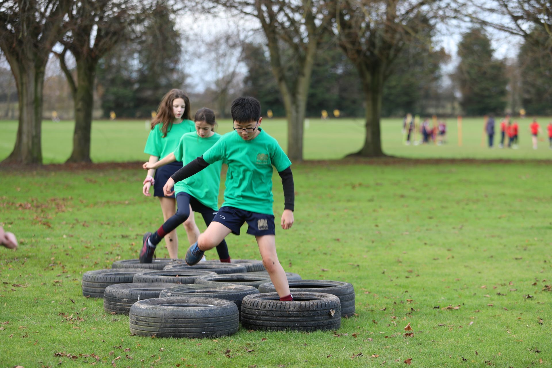 A group of children are playing with tires in a field.