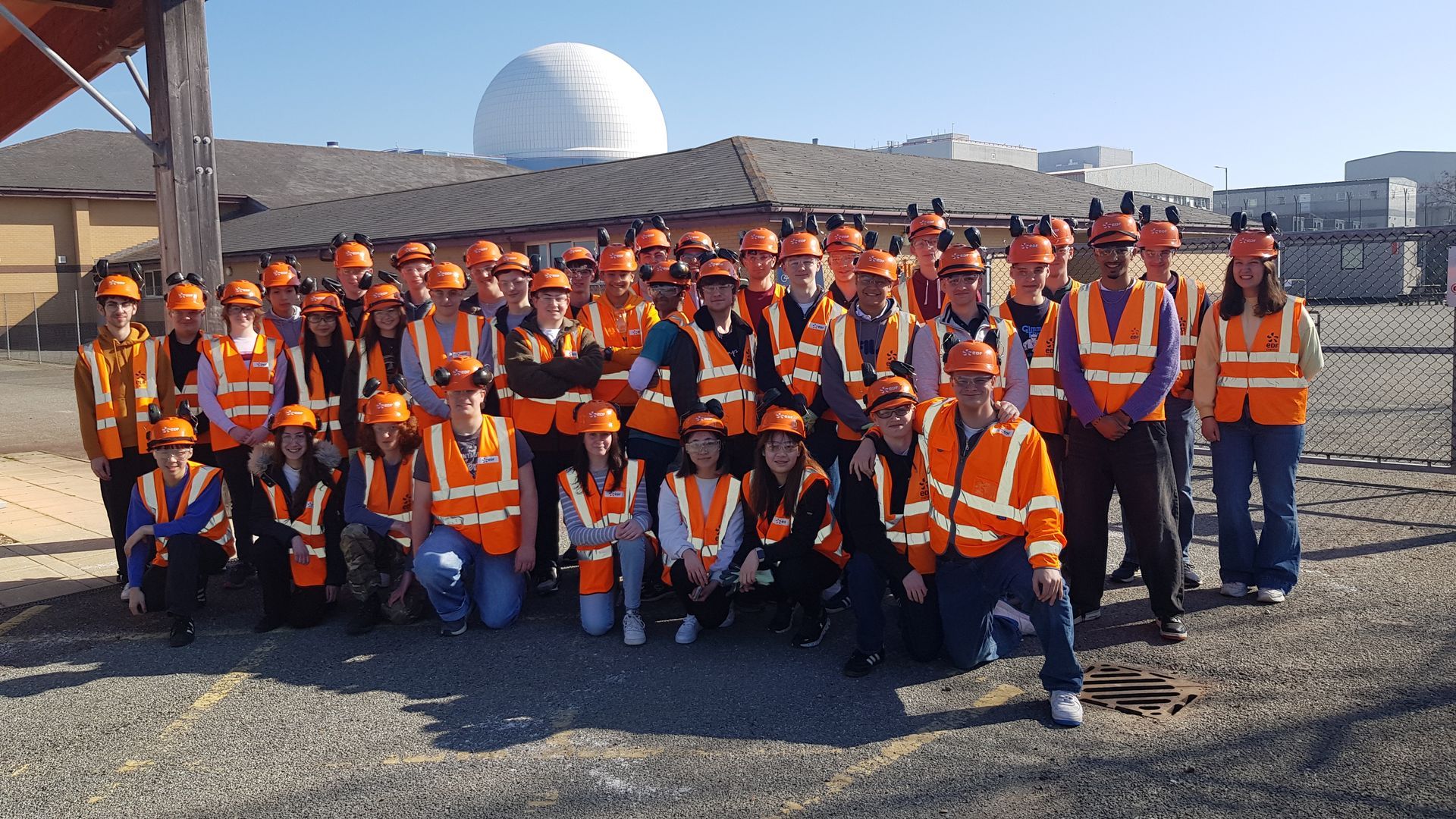 A group of students are sitting at a table in a classroom with a teacher.