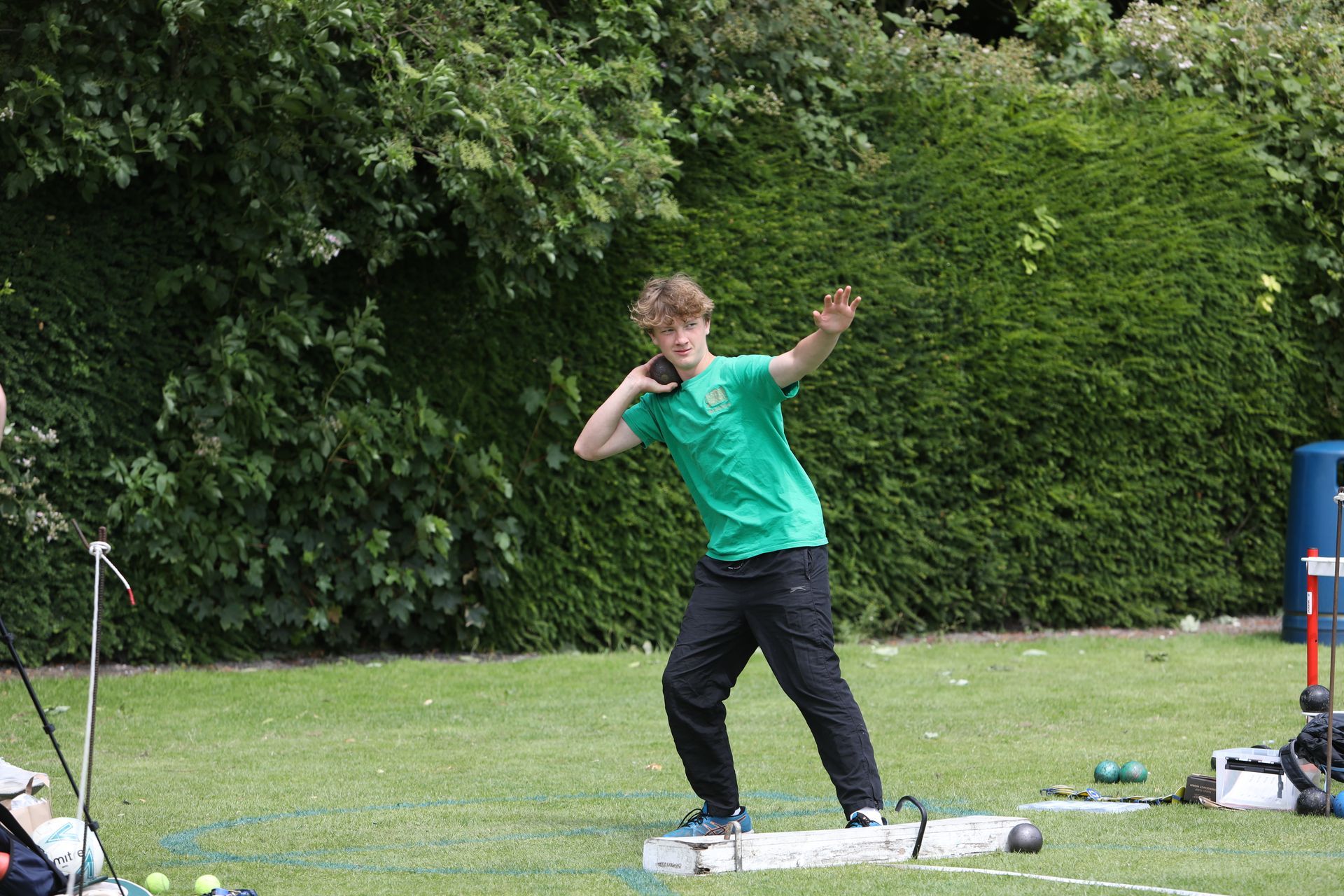 A young boy in a green shirt is throwing a ball in a field.