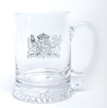 A clear glass mug with a coat of arms on it.
