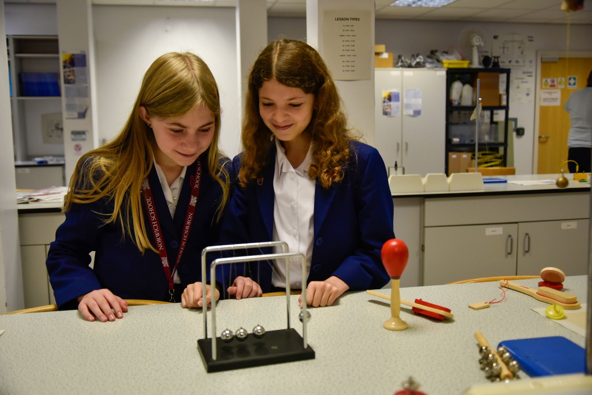 A group of young people in school uniforms are sitting at a table in a classroom.