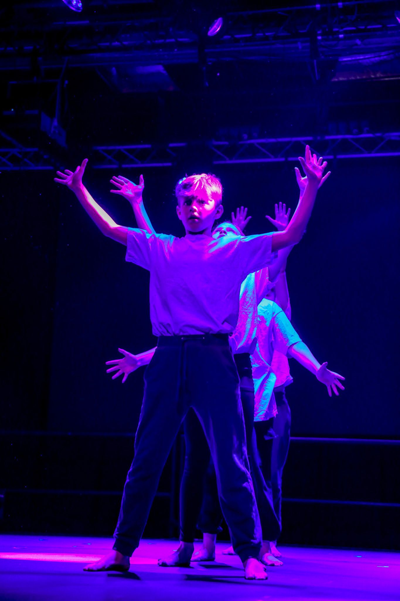 A group of people are dancing on a stage with purple lights.