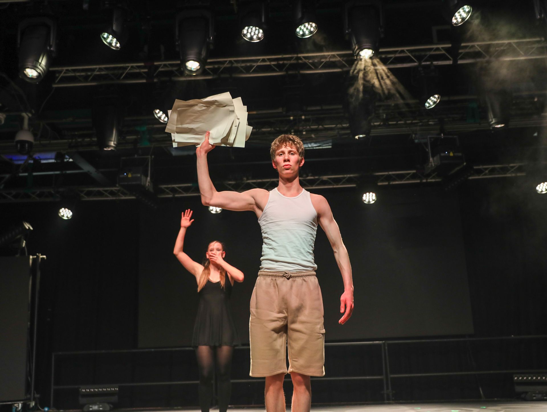 A man is holding a stack of papers in his hand while a woman stands behind him
