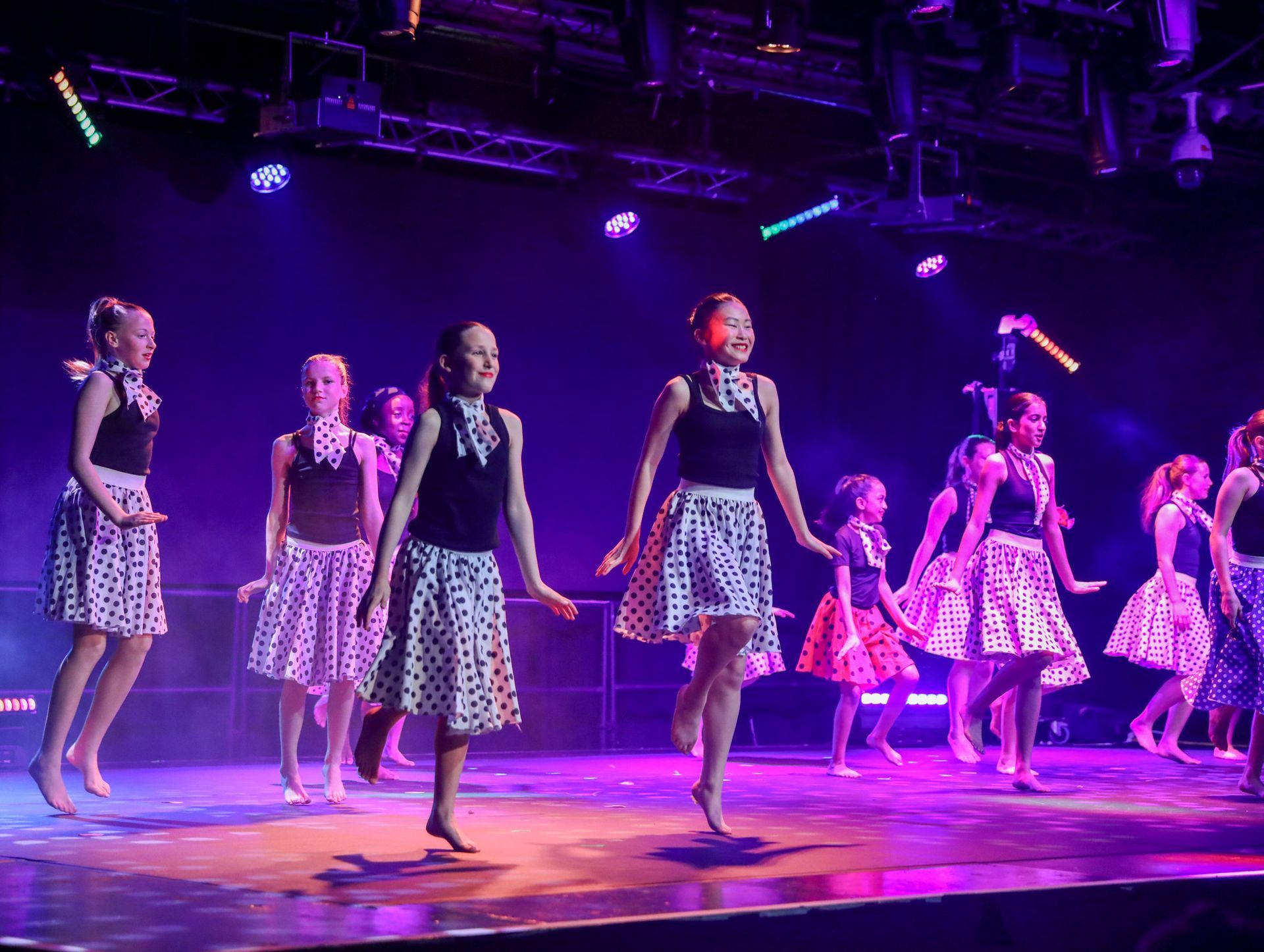 A group of children are standing on a stage with their hands in the air.