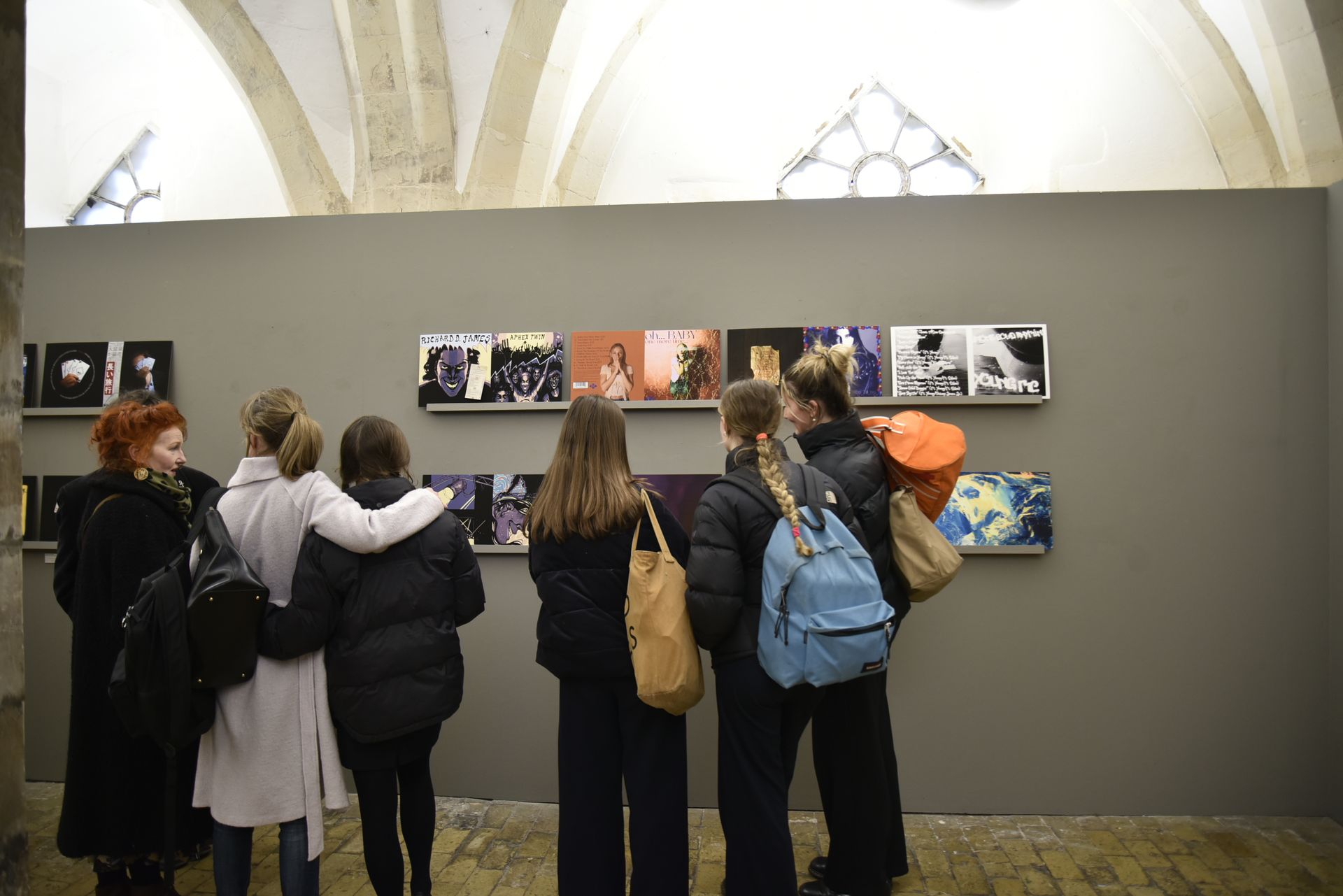 A group of people are looking at pictures on a wall in a museum.