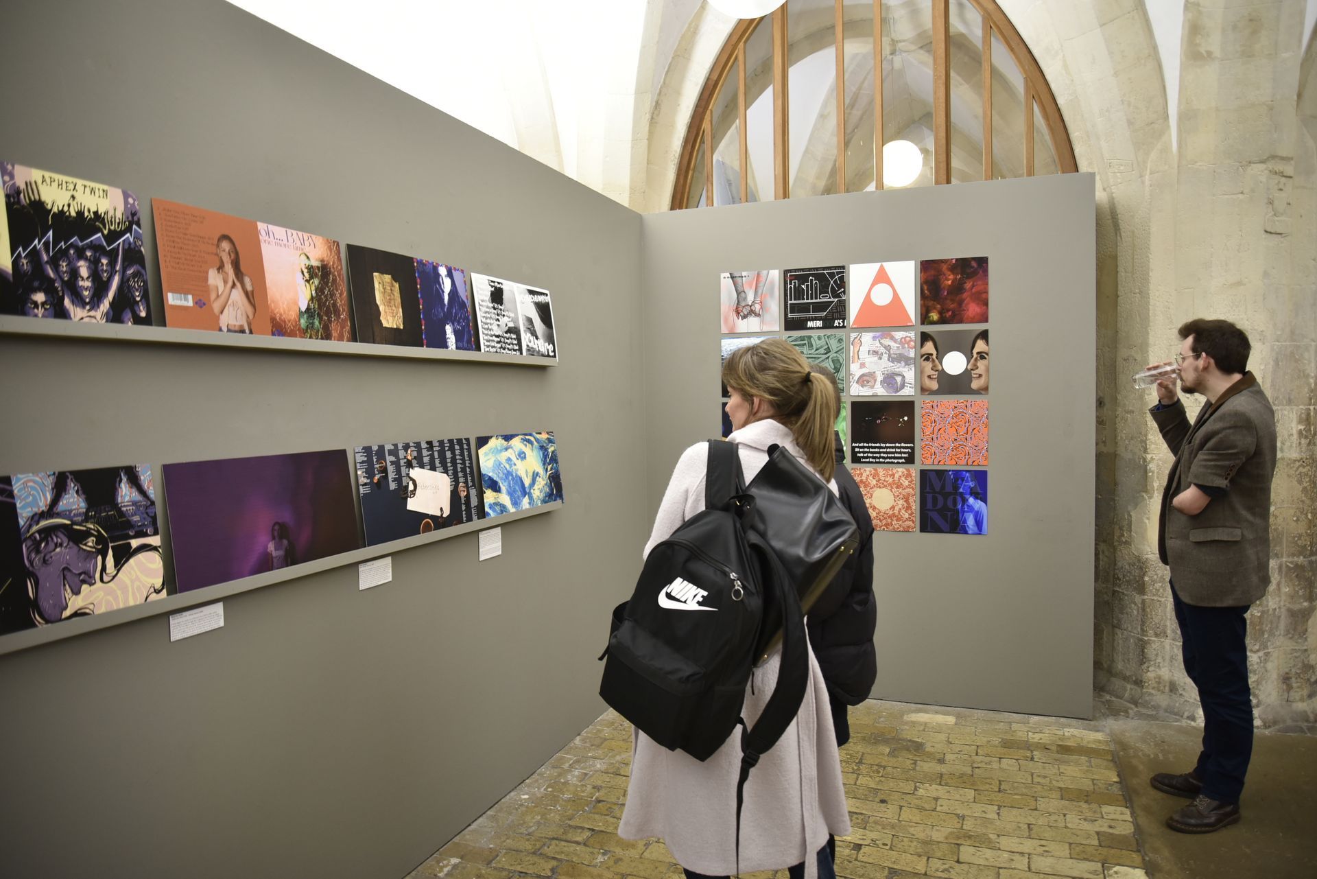 A man and a woman are looking at a wall of pictures in a museum.
