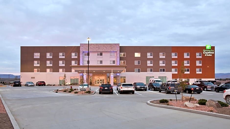 A modern, three-story Holiday Inn Express hotel building at dusk, featuring a large parking lot filled with vehicles.