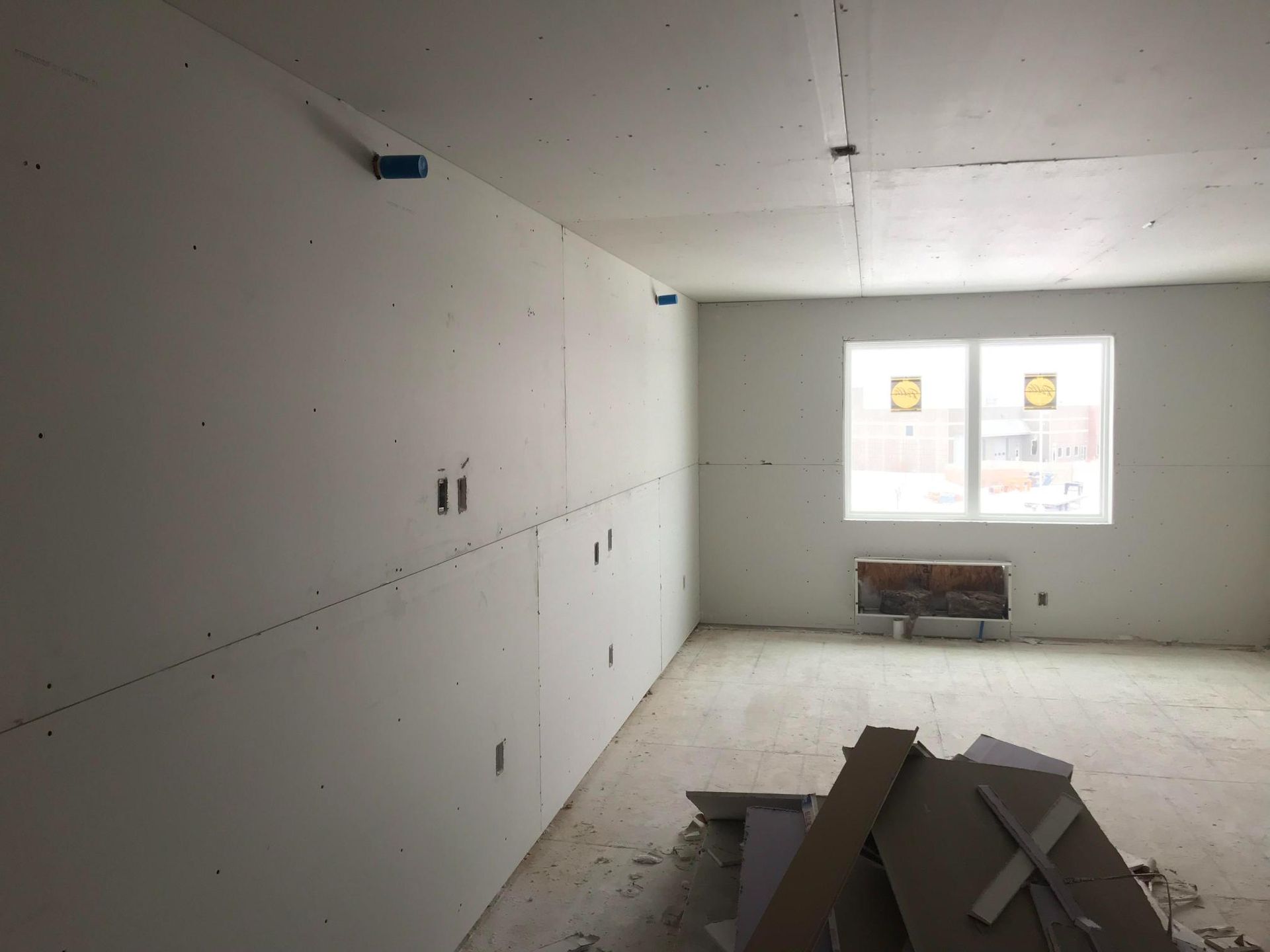 Unfinished room with drywall, exposed floor, and two windows letting in daylight.