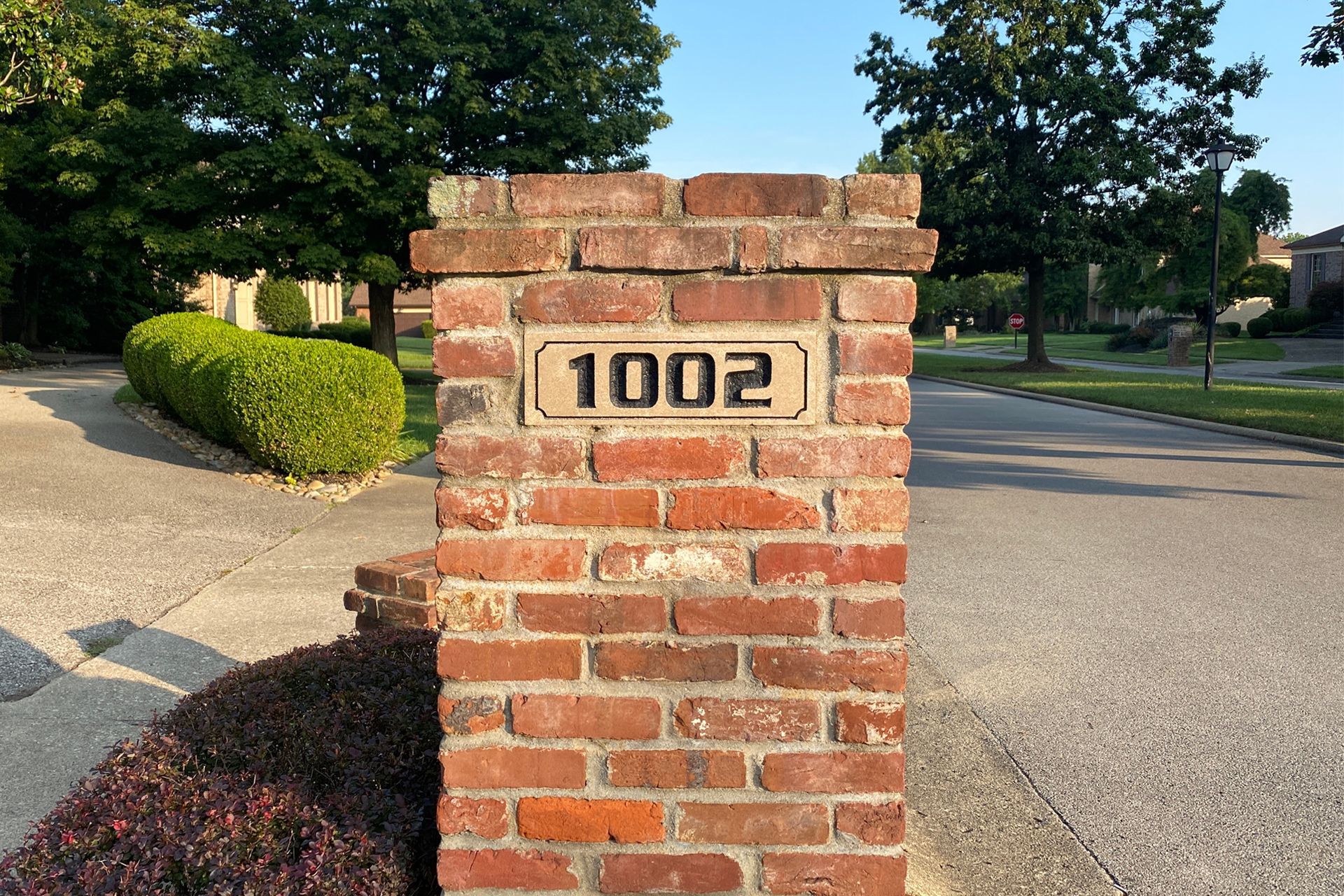 A brick mailbox post with the address number 1002.