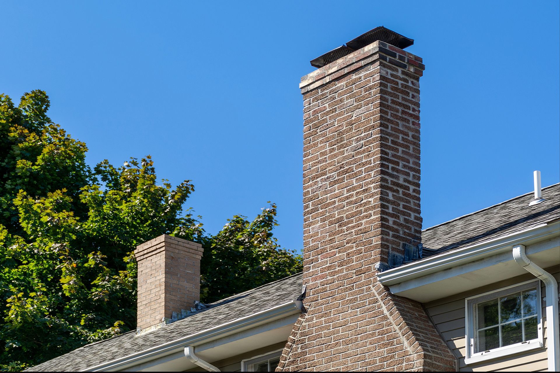 A brick chimney on a house roof.