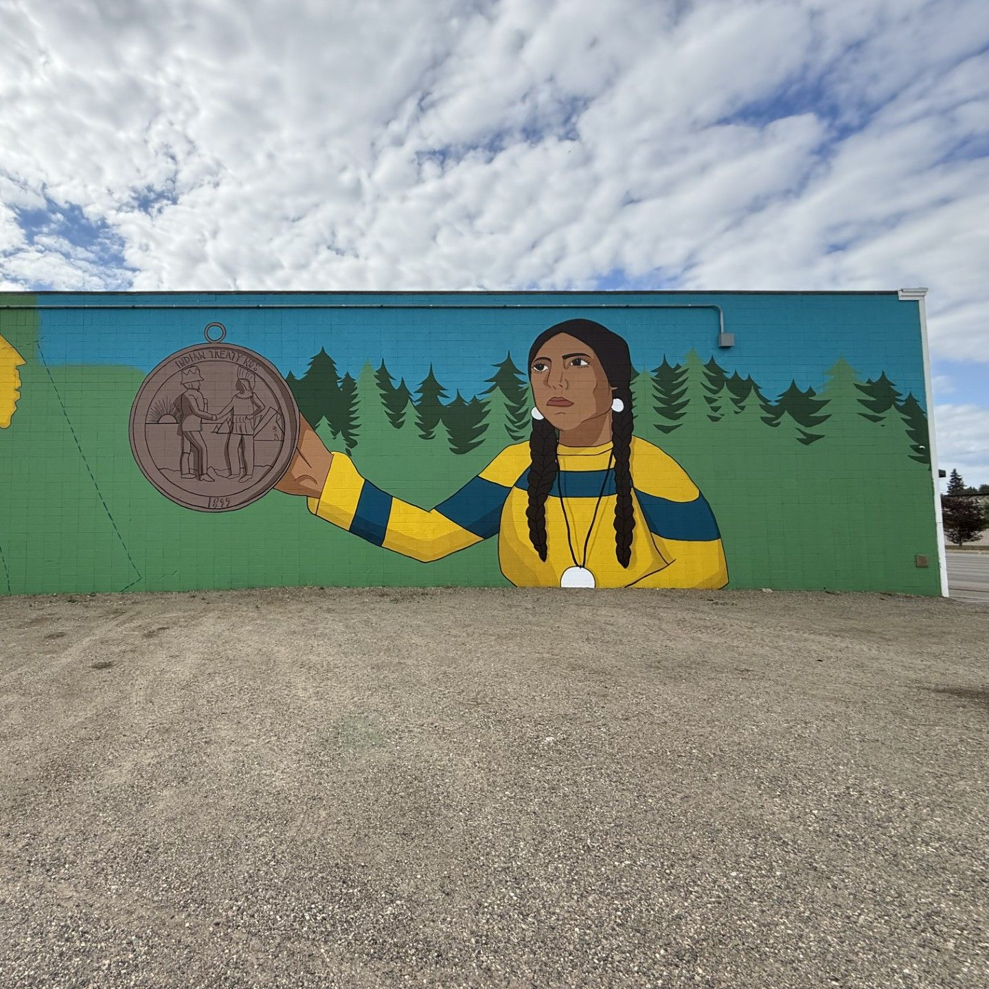 Mural of person holding a large bronze medal with a forest backdrop under a cloudy sky.