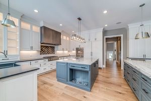 Large kitchen with island surrounded by white quartzite countertops