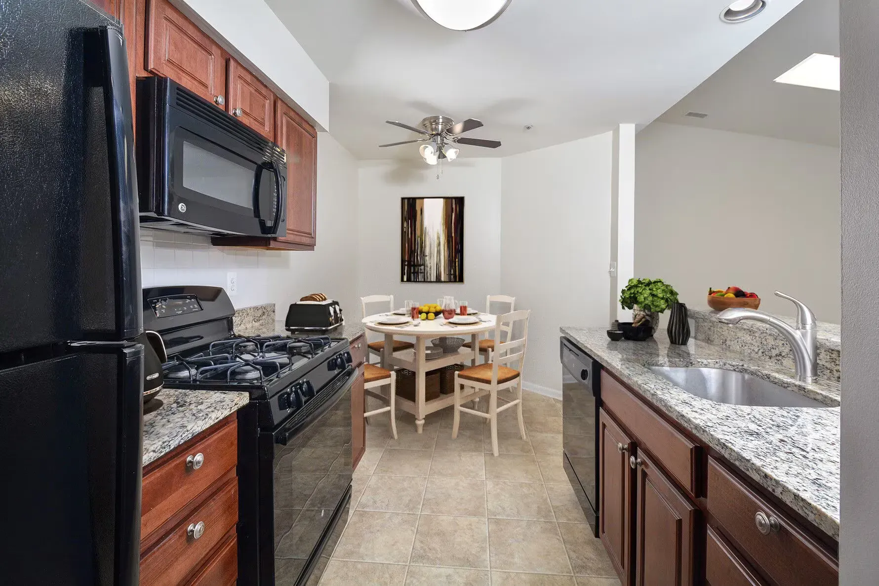 Kitchen with granite countertops, black appliances, and a round dining table.