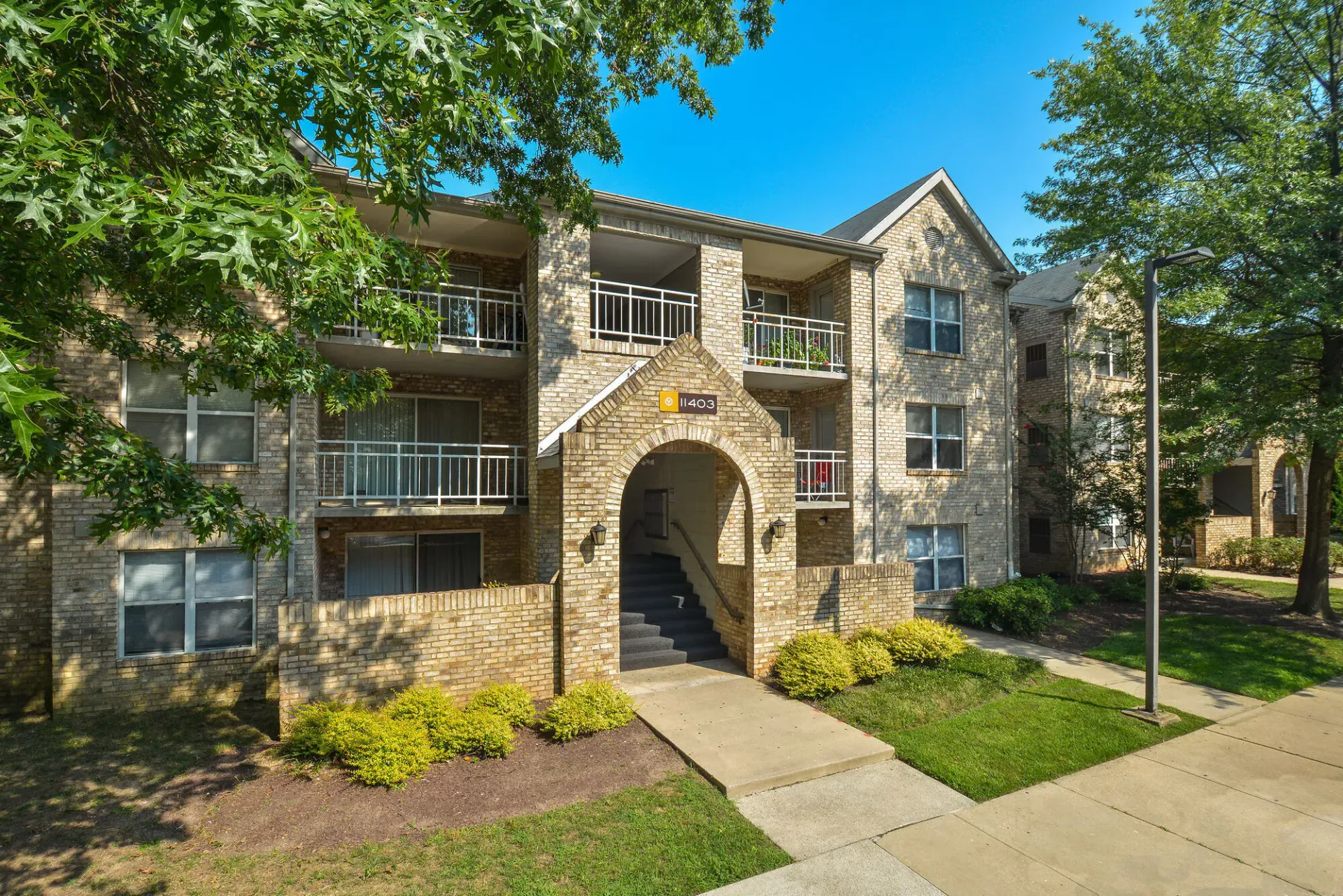 Exterior view of a brick apartment building with arched entry and balconies.