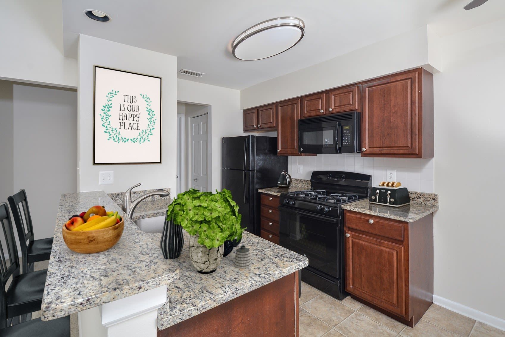 Kitchen area with granite island, dark wood cabinets, and black appliances.
