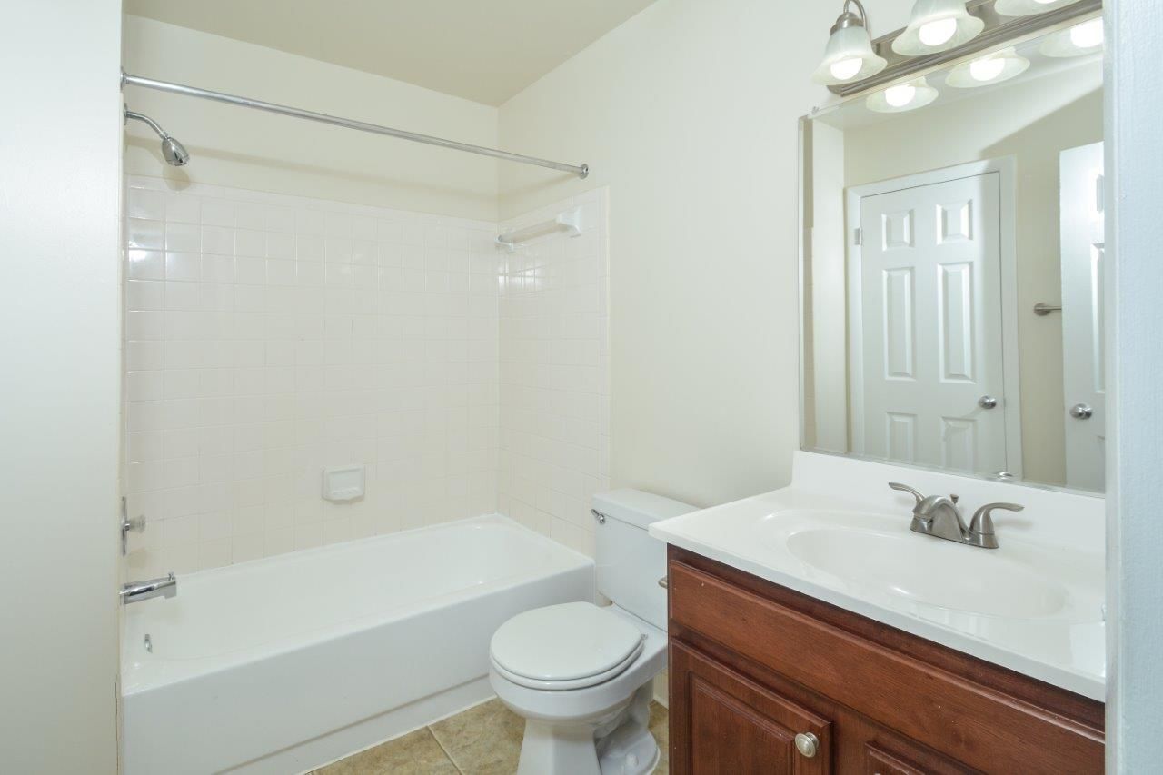 Bathroom with tub/shower, toilet, and vanity in an apartment unit.