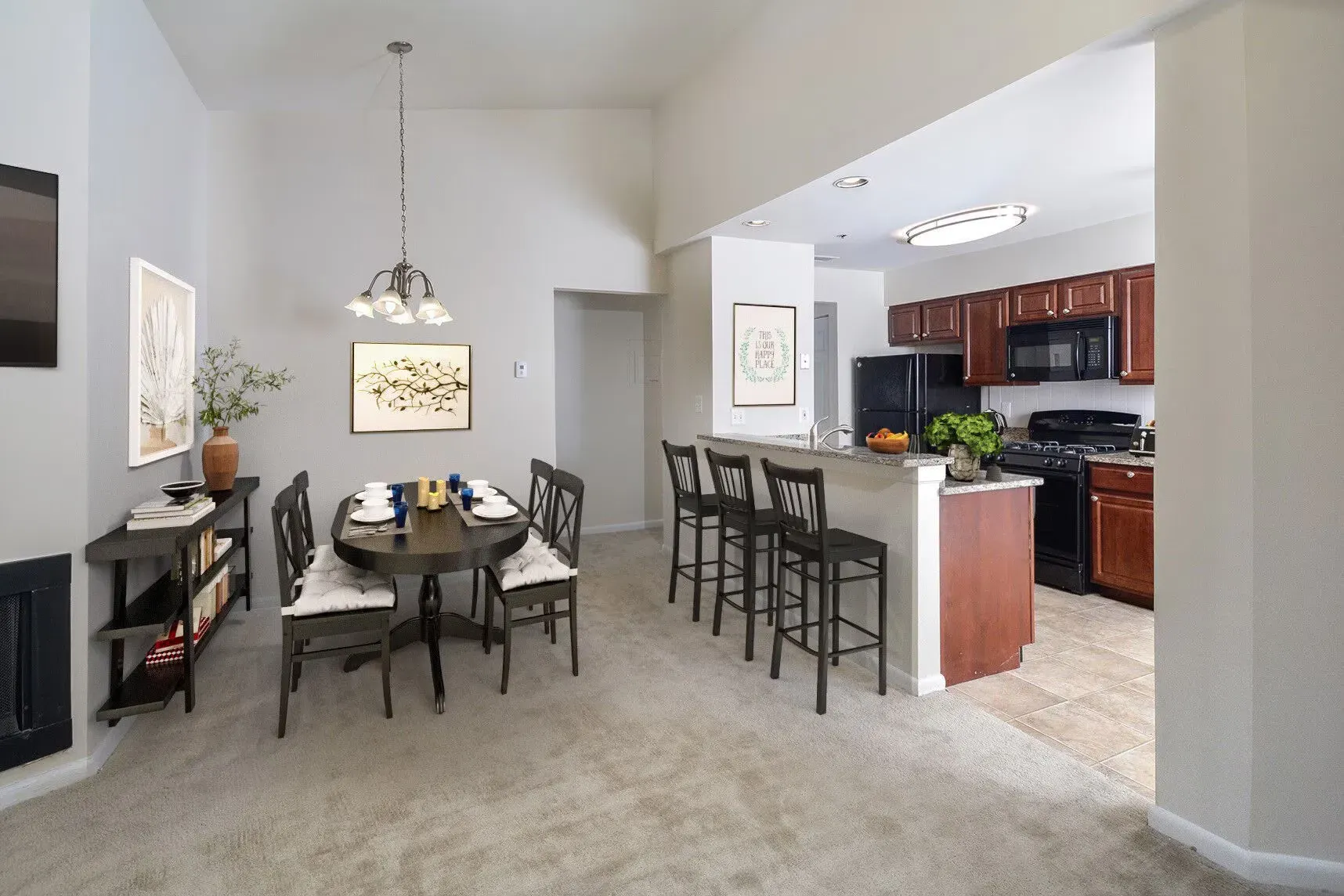 Open-concept dining area with a kitchen island and bar stools in an apartment.