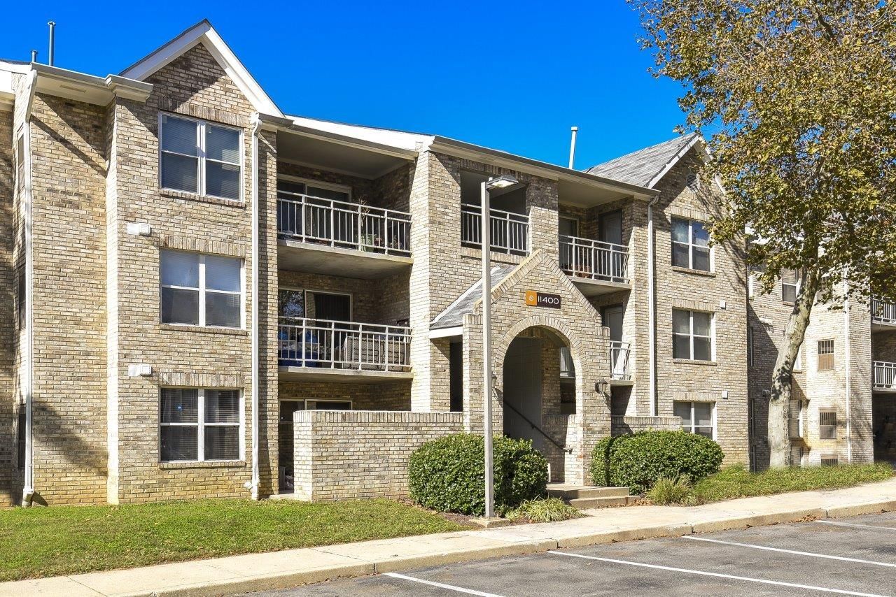 Exterior view of a brick apartment building with balconies and a central arched entrance.