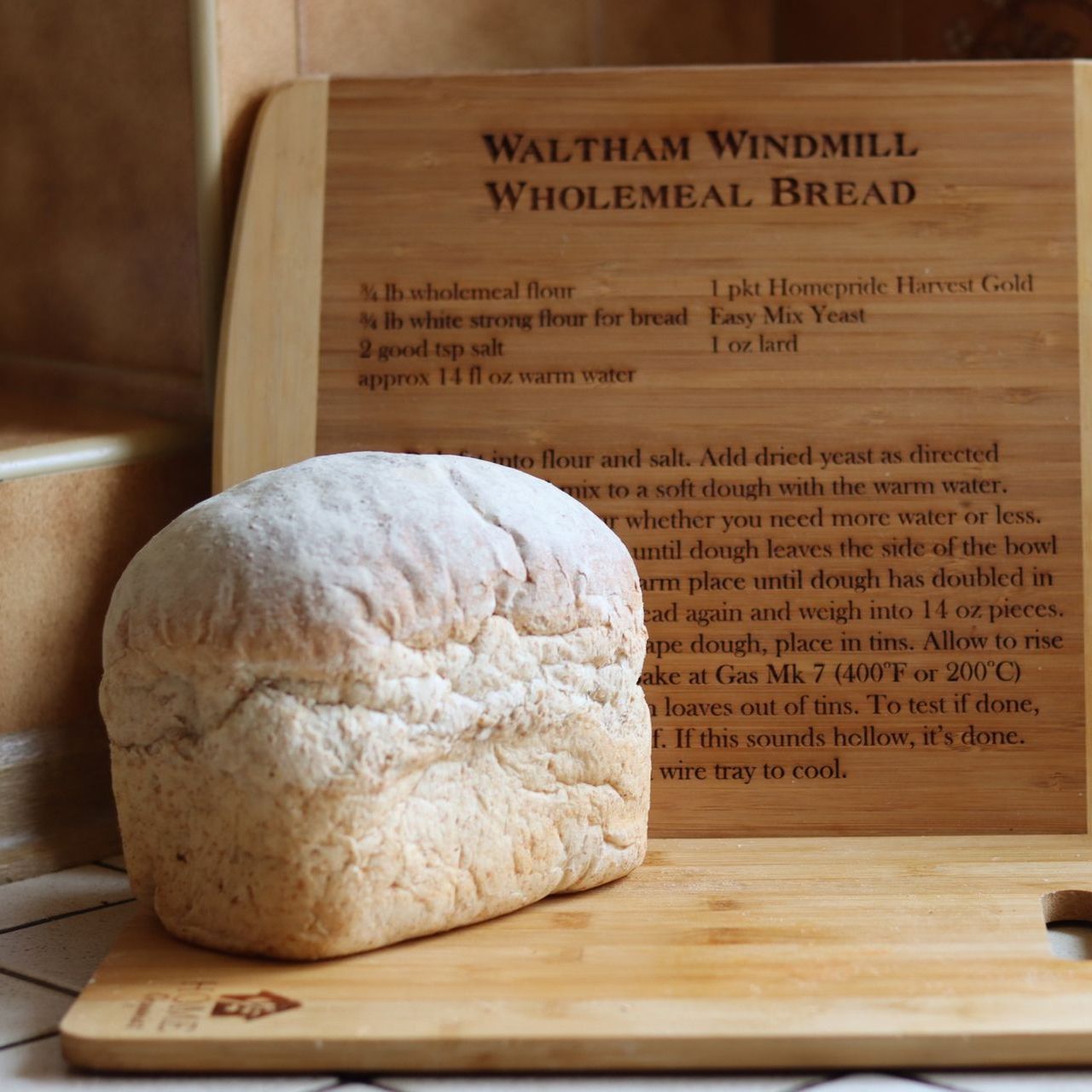A loaf of waltham windmill wholemeal bread sits on a wooden cutting board