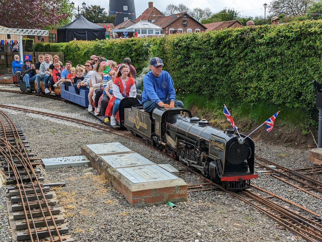 A group of people are riding a small train on a track.