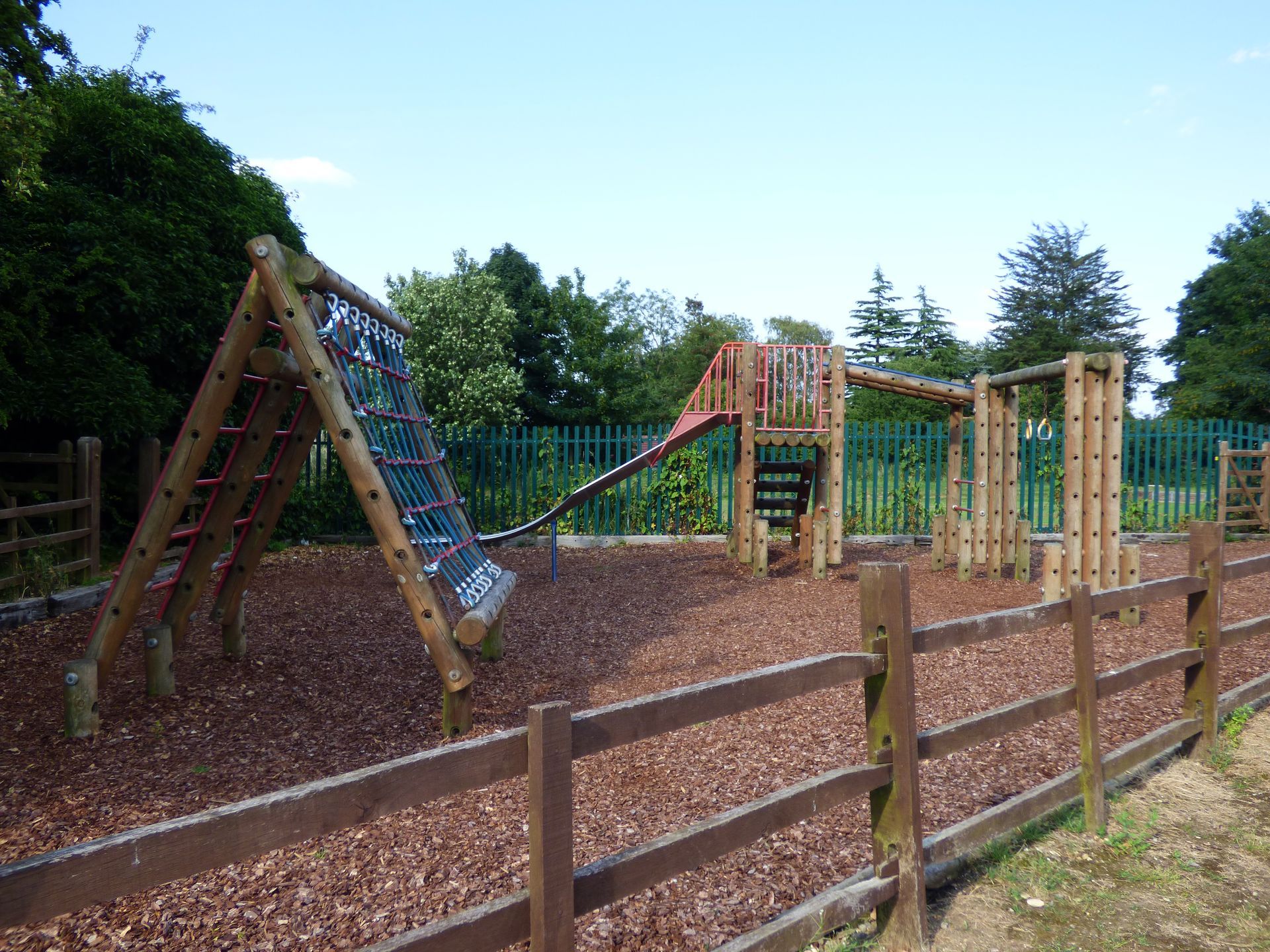 A wooden playground with a wooden fence surrounding it