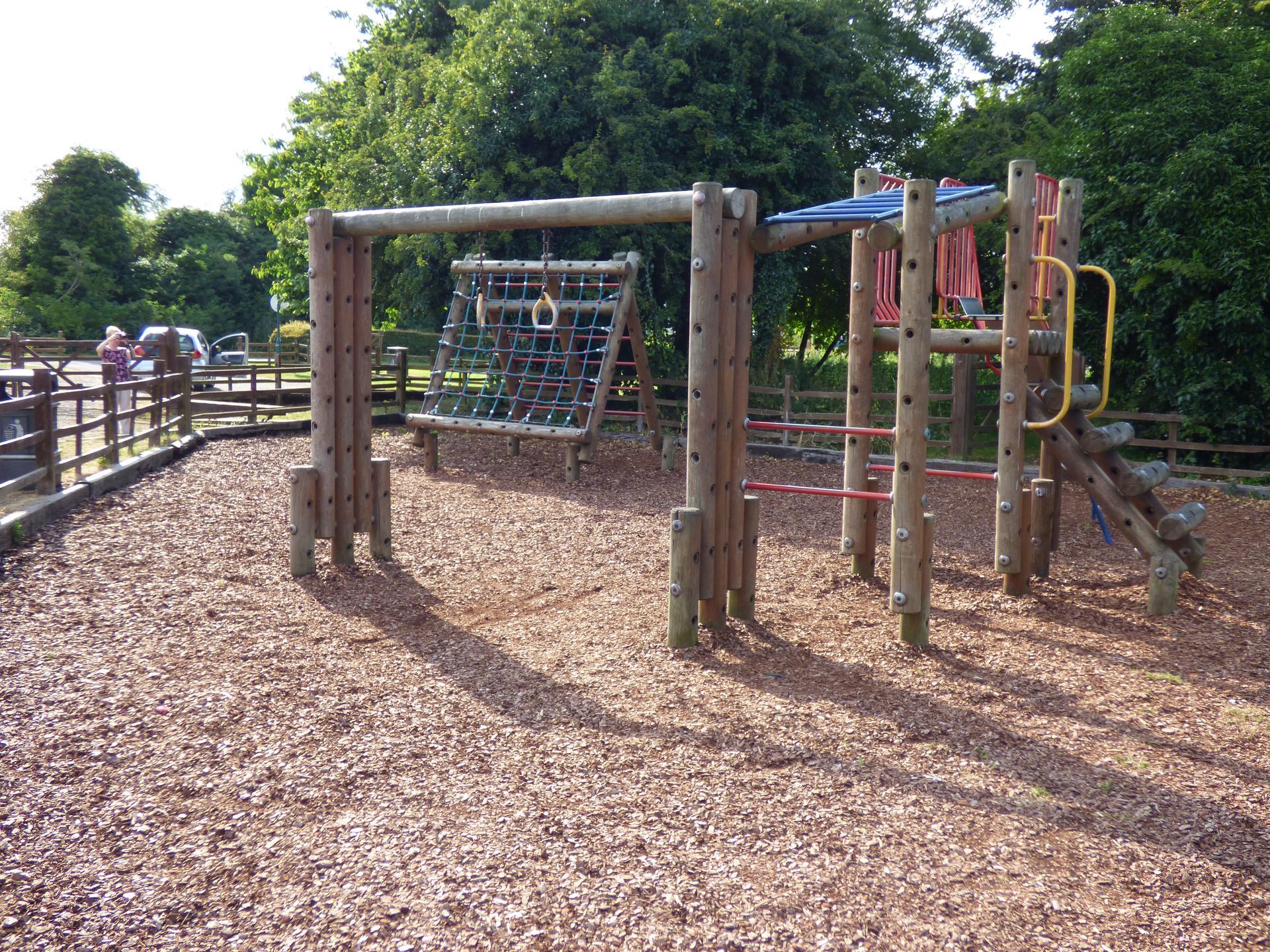 A wooden playground with a swing set and a slide