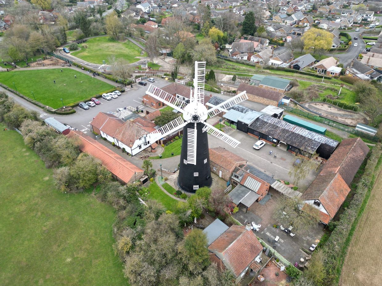 An aerial view of a windmill in the middle of a field surrounded by buildings.