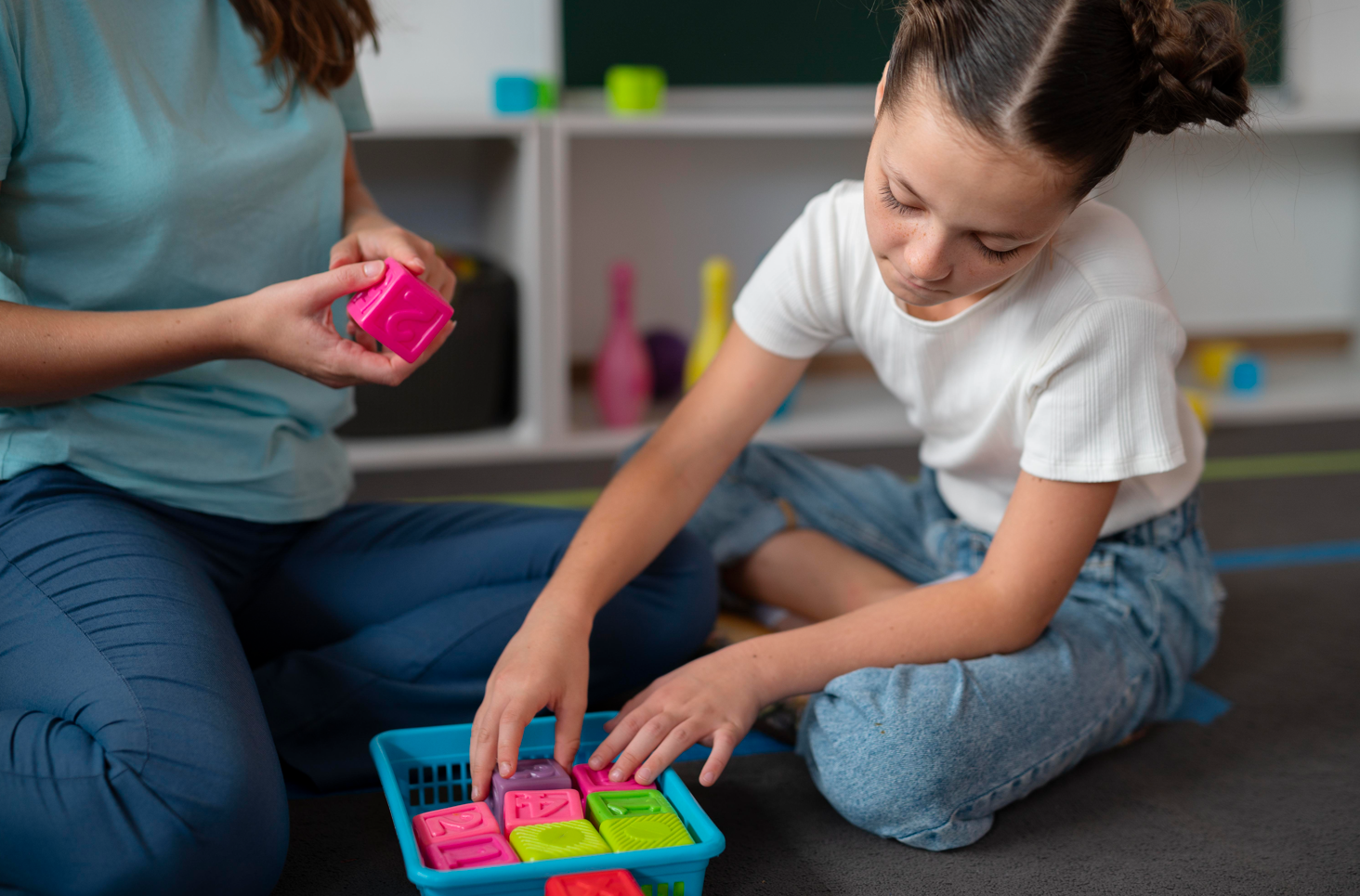 Una mujer y una niña jugando con bloques de colores en el suelo de una habitación.