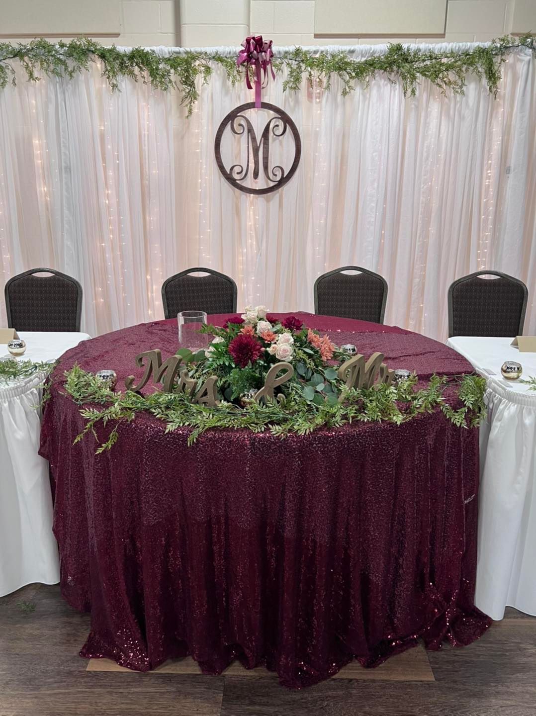 A table with a burgundy tablecloth and flowers on it.