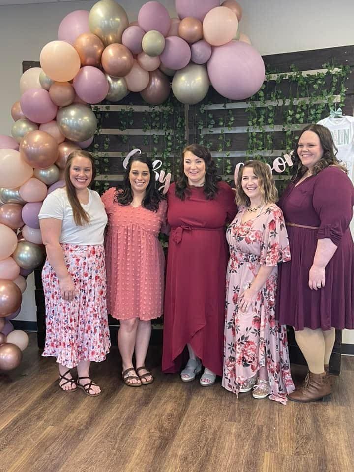A group of graduates are smiling and holding their diplomas.