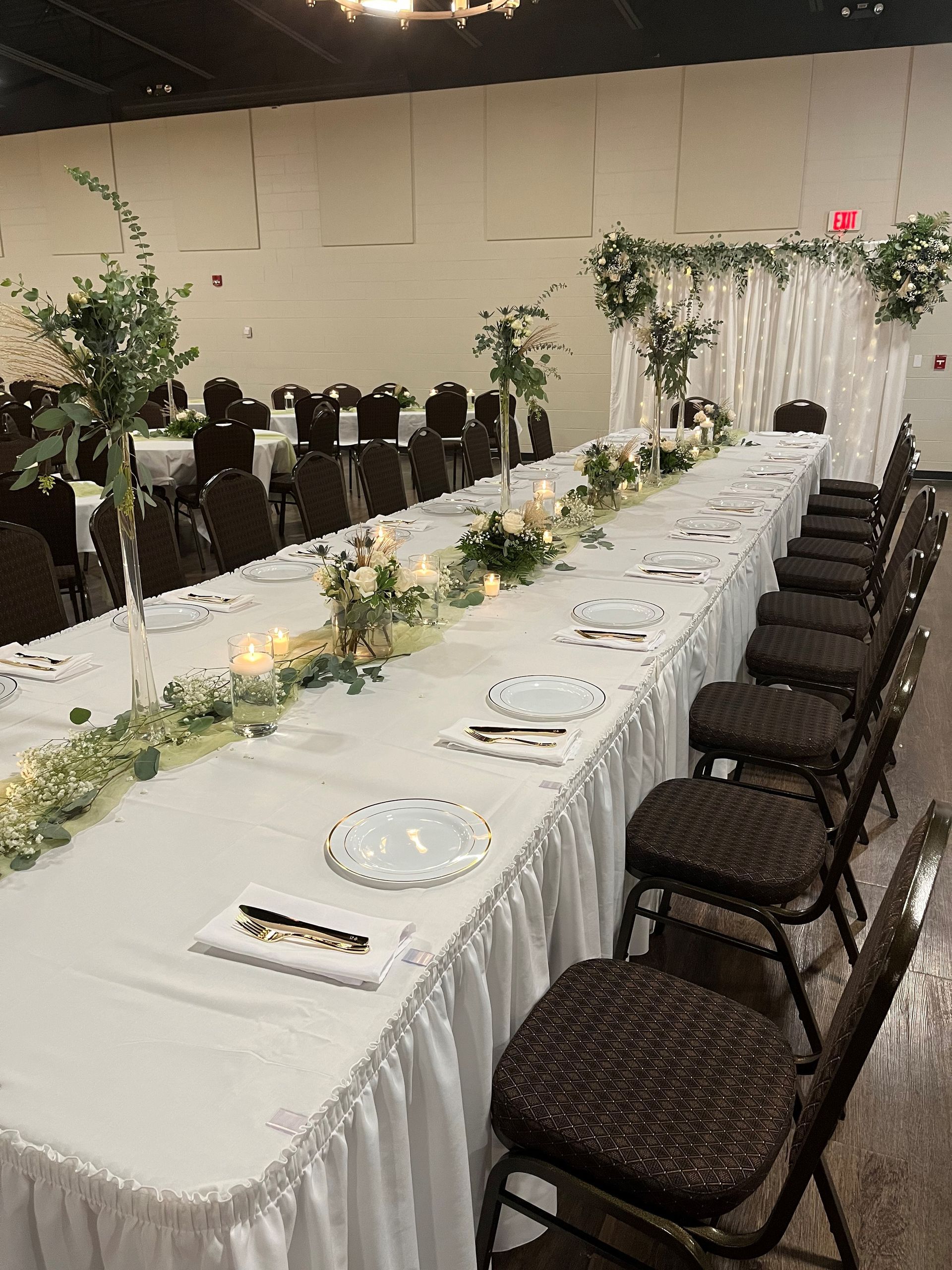 A long table with plates , napkins , and candles on it in a room.