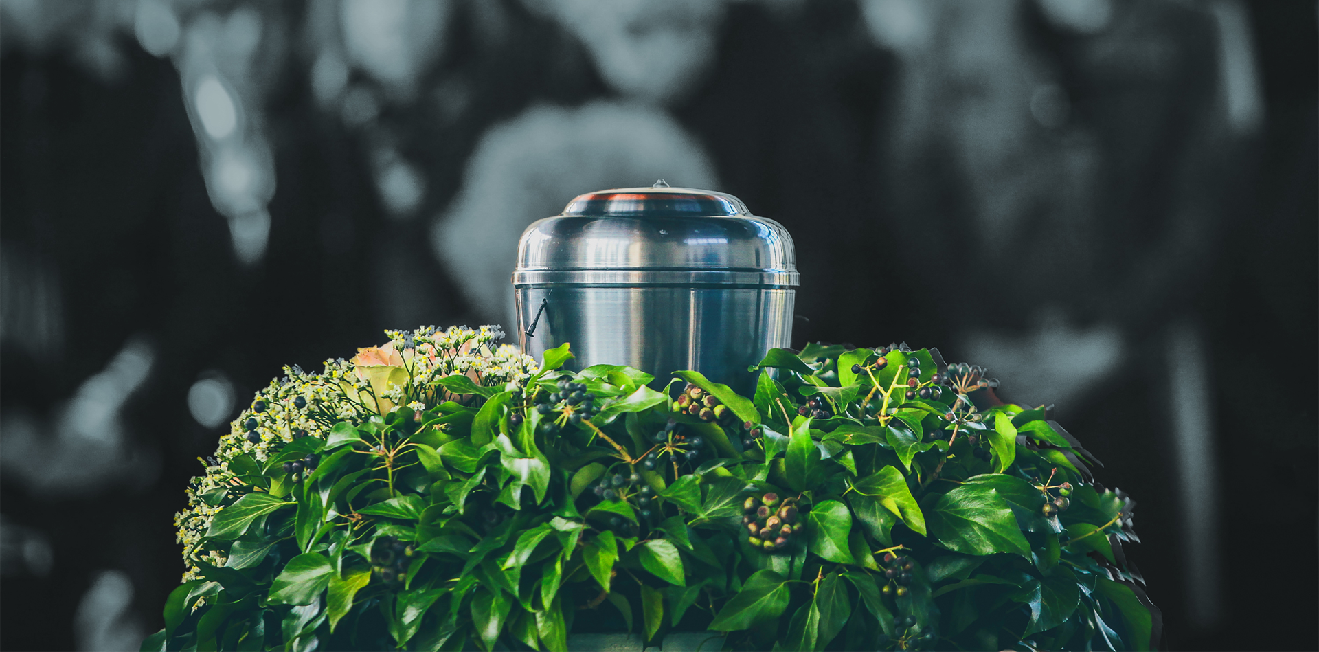 A urn is surrounded by a wreath of green leaves at a funeral.