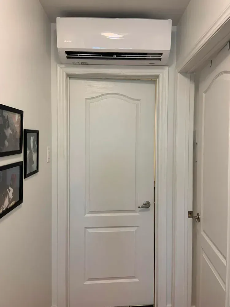 Une porte blanche avec un climatiseur monté au plafond au-dessus.