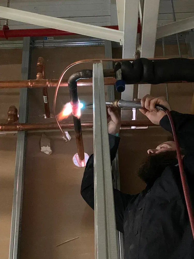 Un homme coupe des tuyaux en cuivre avec un chalumeau.