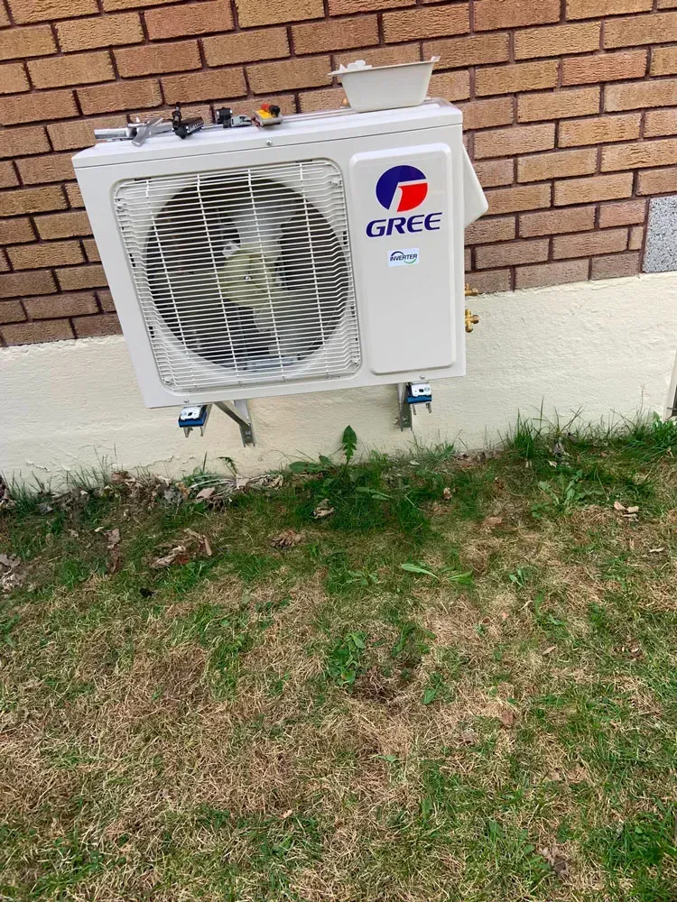 Un climatiseur gree est posé sur le côté d'un bâtiment en briques.