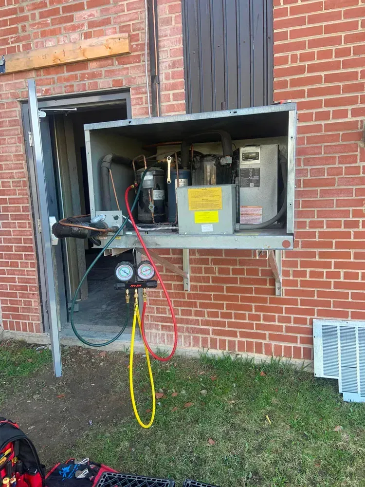 Un réfrigérateur est en cours d'installation sur le côté d'un bâtiment en briques.