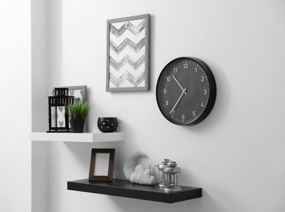 A Black Clock Is Hanging on A White Wall Next to A Shelf — The Framer In Taree, NSW