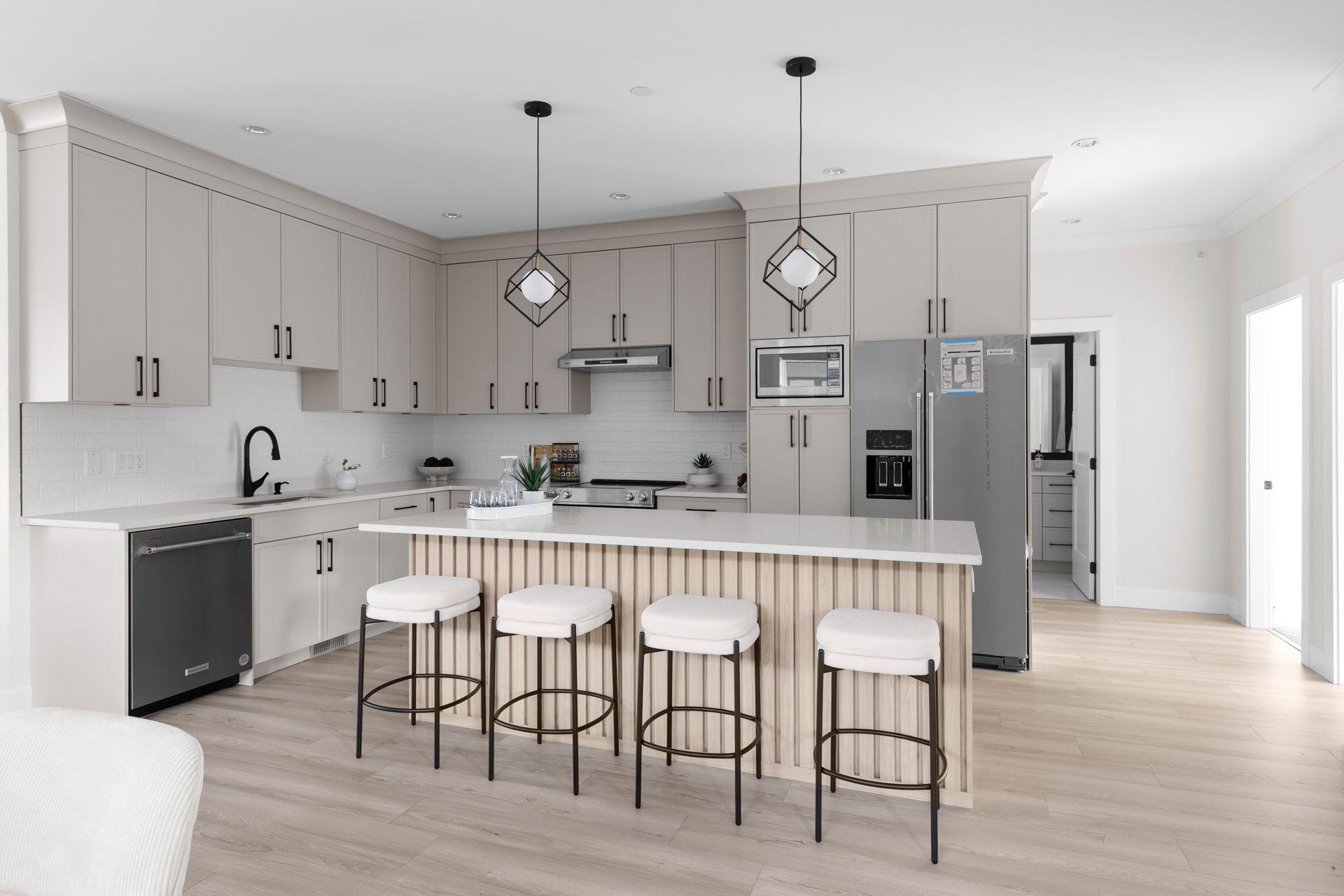 Modern gray kitchen with island, bar stools, pendant lights, and stainless steel appliances