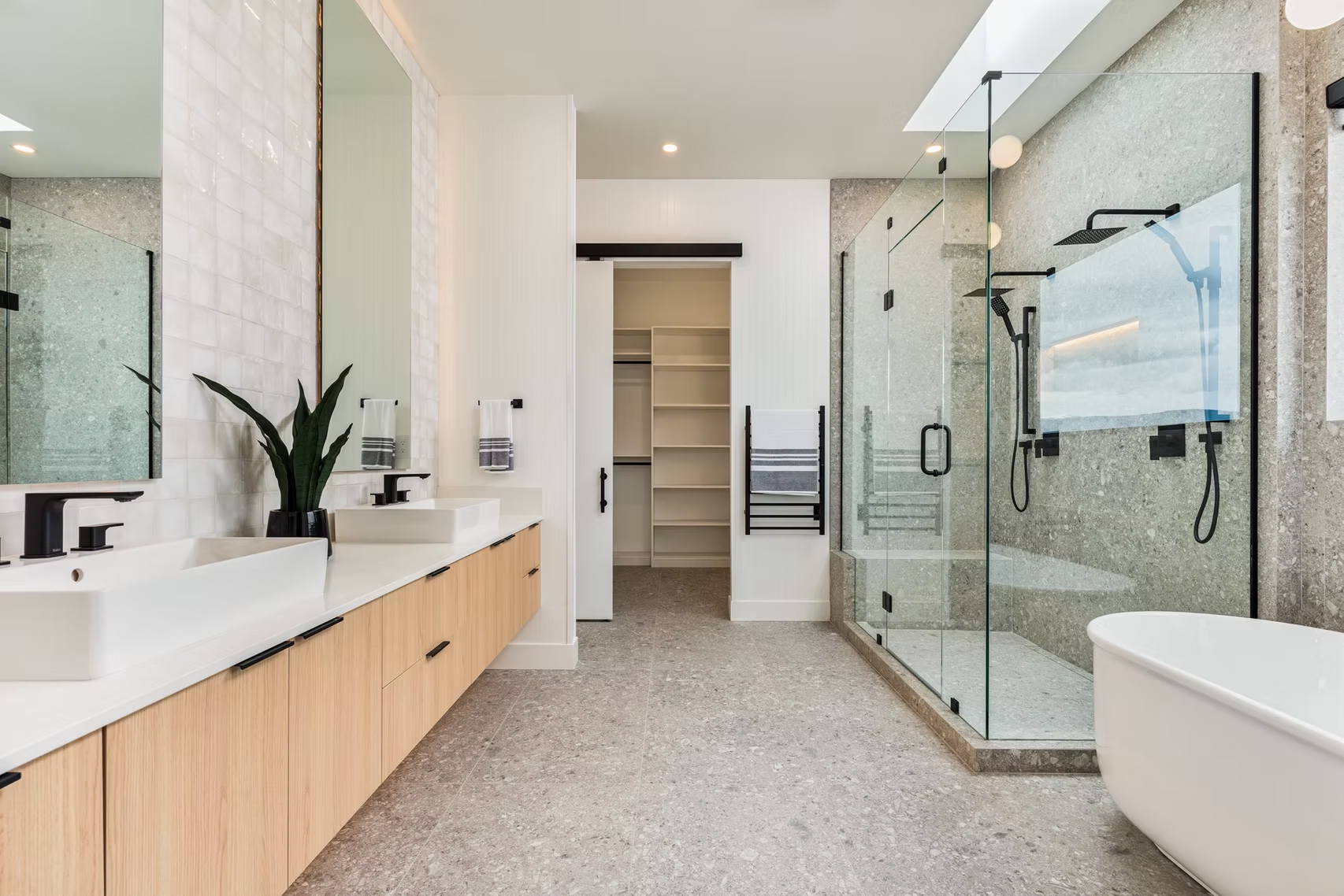Bright modern bathroom with glass shower, double vanity, and freestanding tub