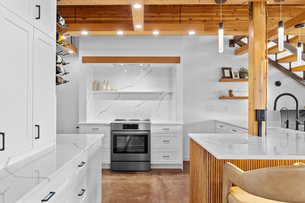 Bright modern white kitchen with wood beams, island, and stainless steel appliances