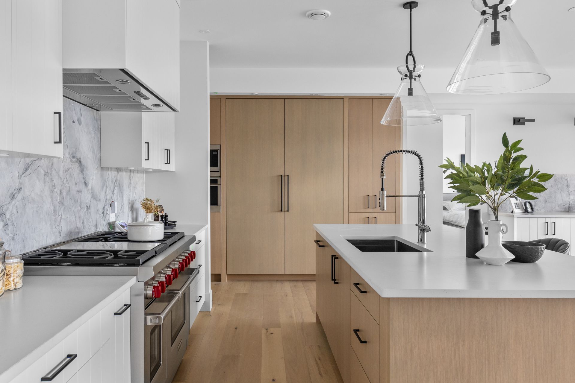 Modern kitchen with white cabinets, wood island, marble backsplash, and stainless steel appliances