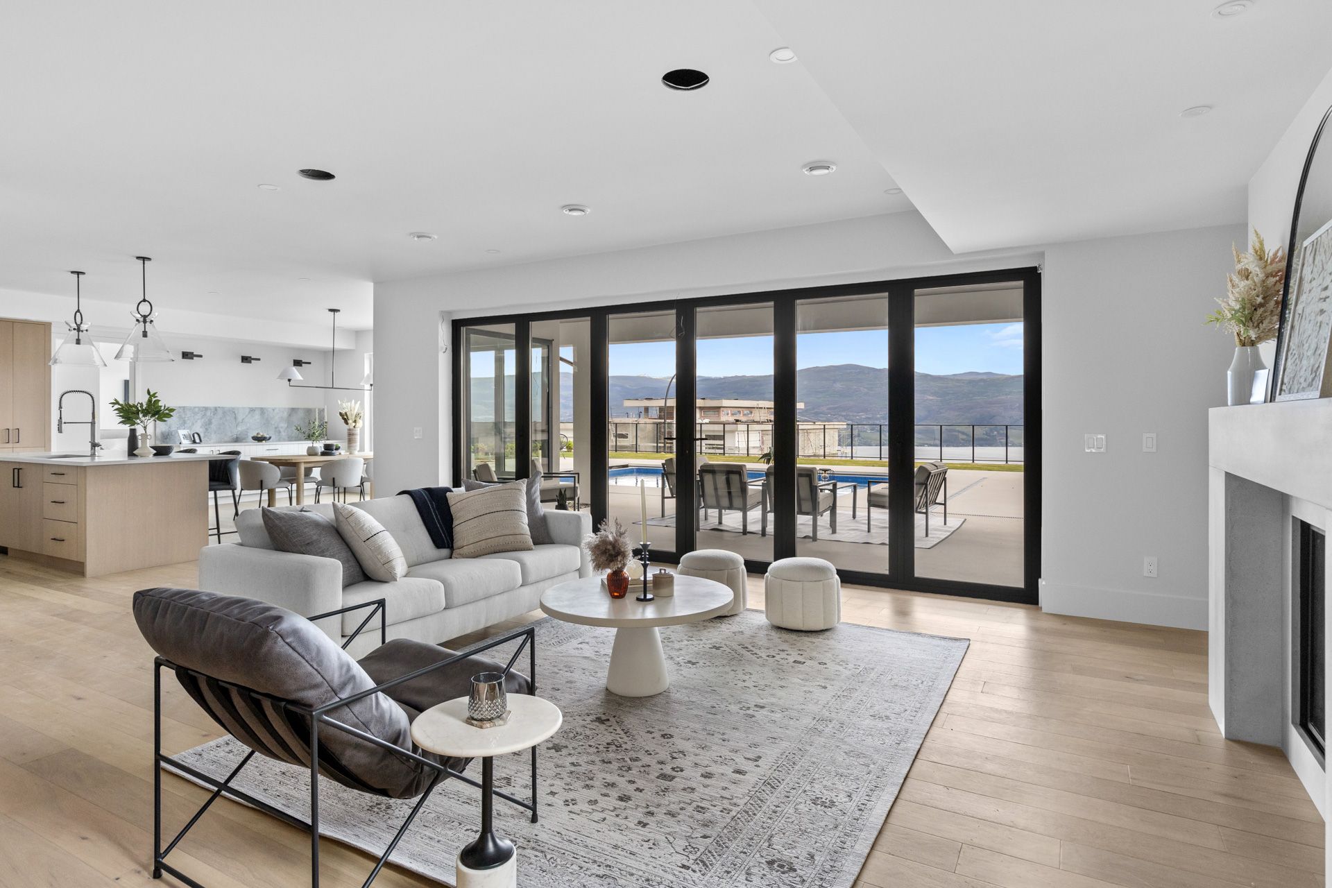 Bright modern living room with sectional seating, fireplace, and large glass doors opening to a balcony.