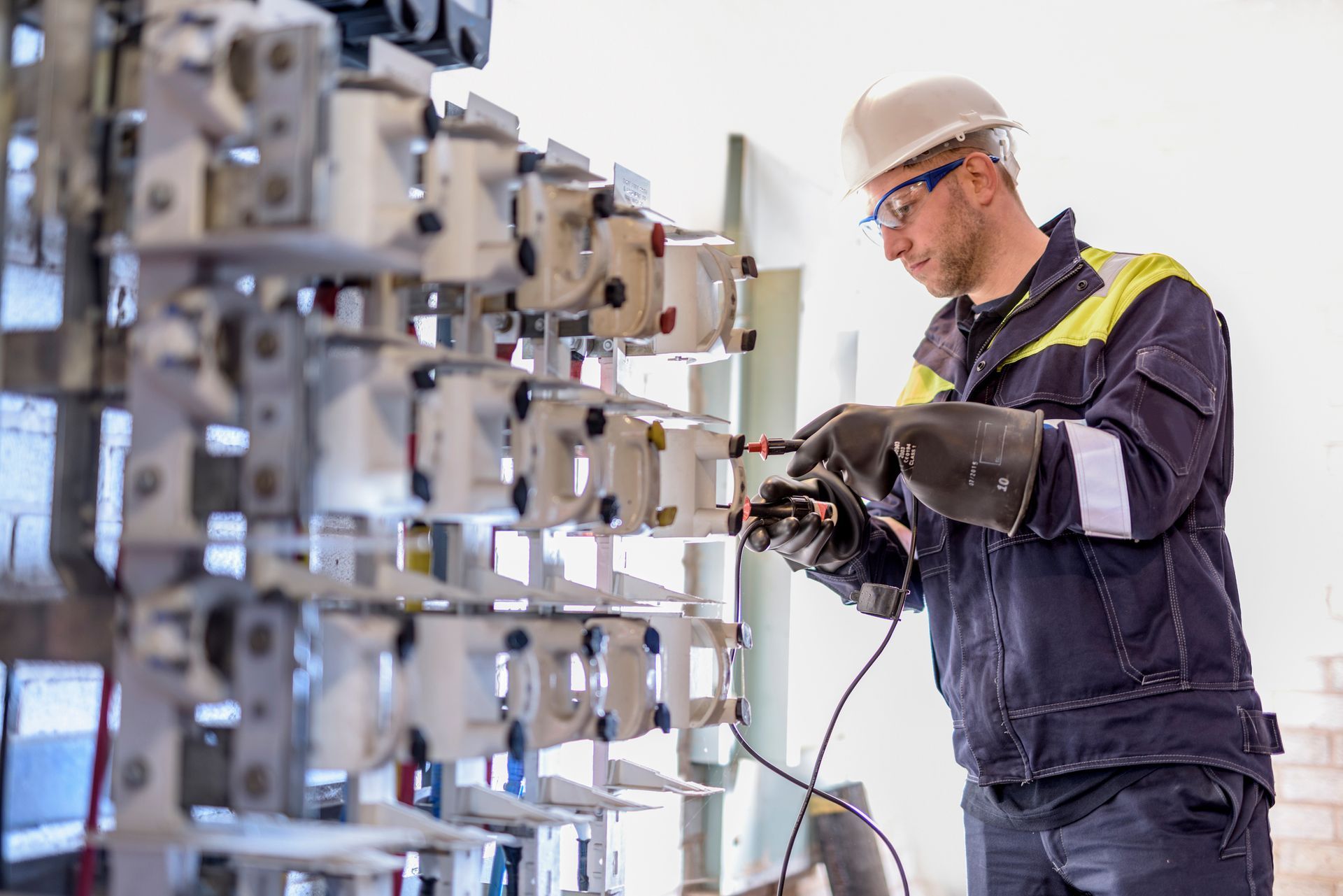 Worker testing circuit breakers in electricity substation. Worker testing circuit breakers in electricity substation.