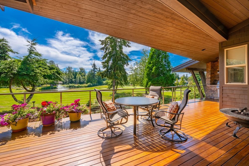 A wooden deck with a table and chairs and a view of a golf course.