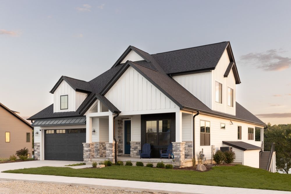 A white house with a black roof and a black garage door.